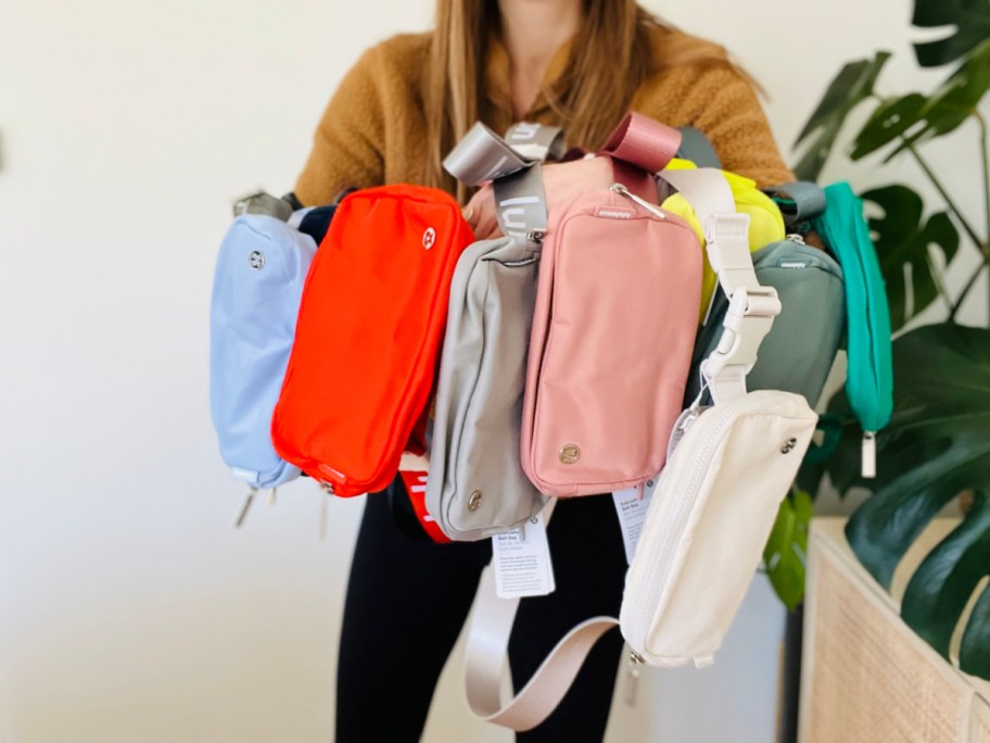 woman holding up different colored lululemon belt bags