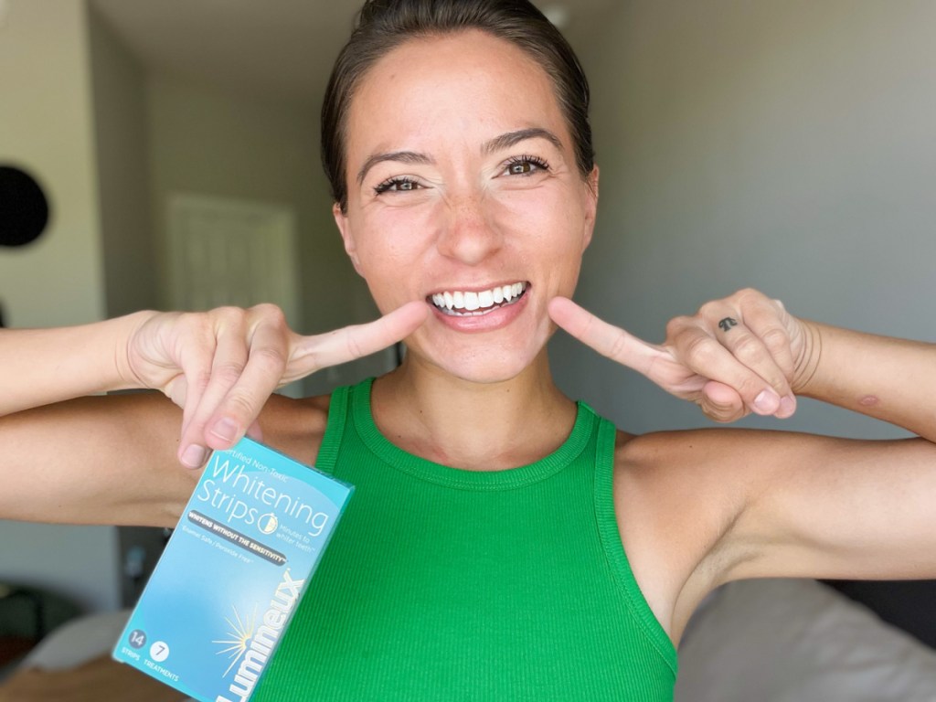 Woman pointing to the results of her Lumineux Teeth Whitening Strips