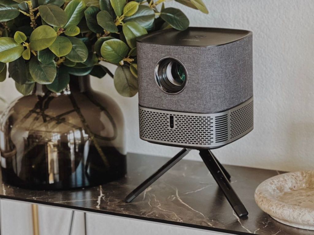 Mudix Projector on tripod on a mantel next to a plant