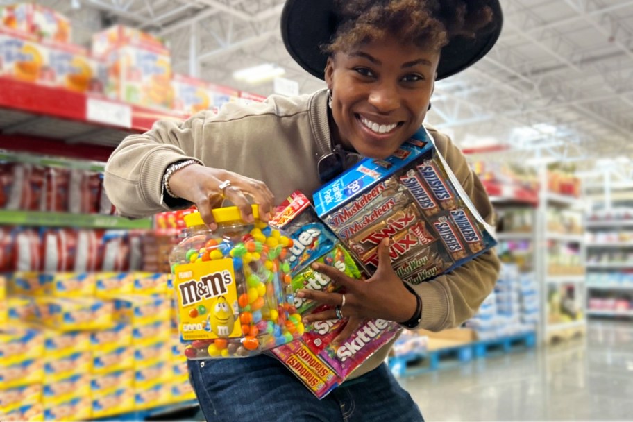 woman holding up armful of candy at sam's club