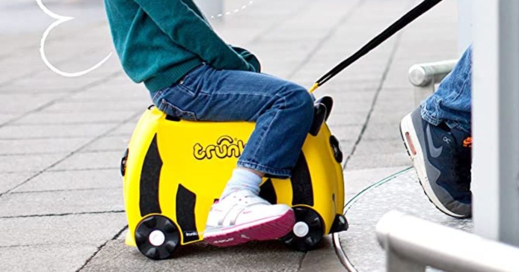 Child riding on Bee-themed Trunki ride-on suitcase