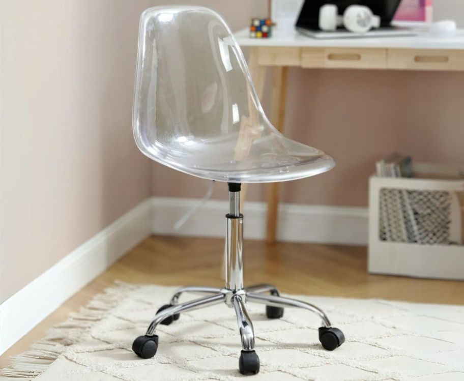 a clear acrylic rolling desk chair in a bedroom in front of a desk