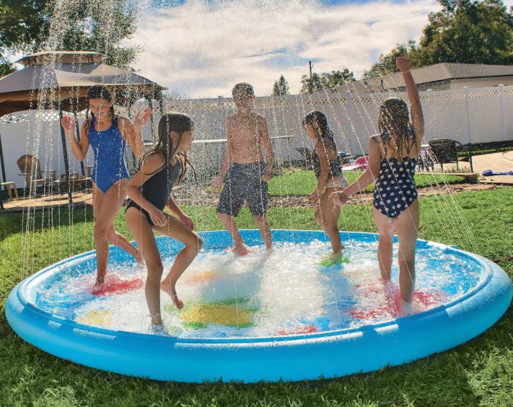 big kids playing in sprinkler outside in backyard