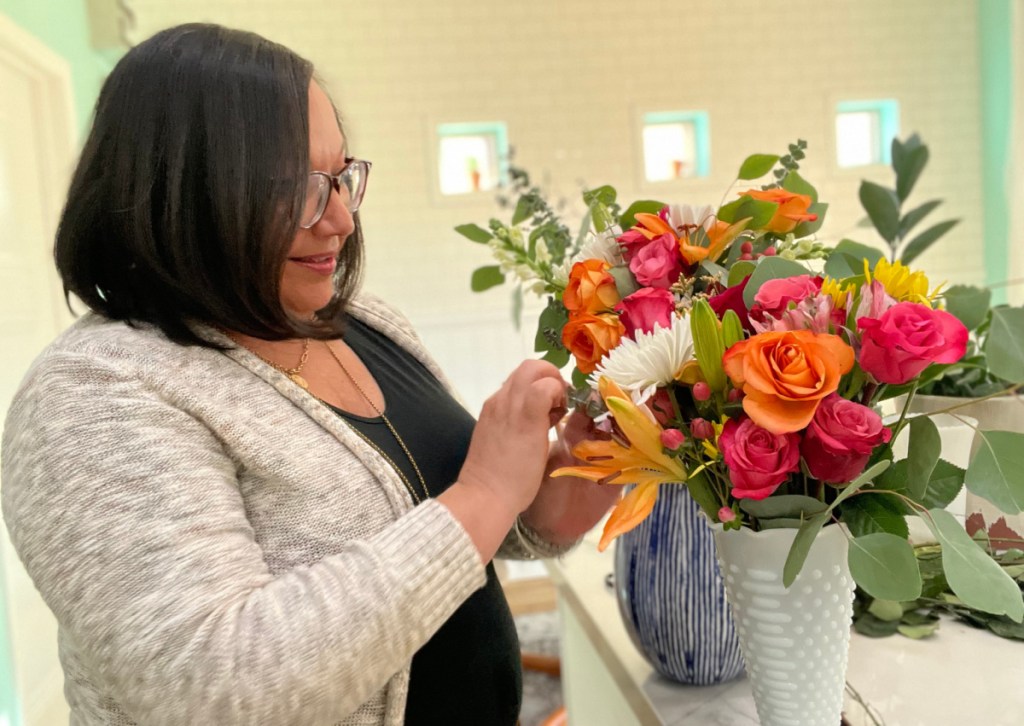 Woman creating a bouquet of grocery store flowers at her kitchen counter