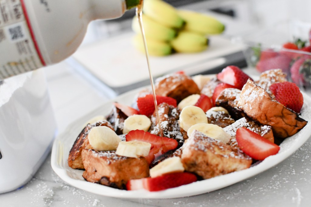 adding syrup to Hawaiian roll french toast on a plate