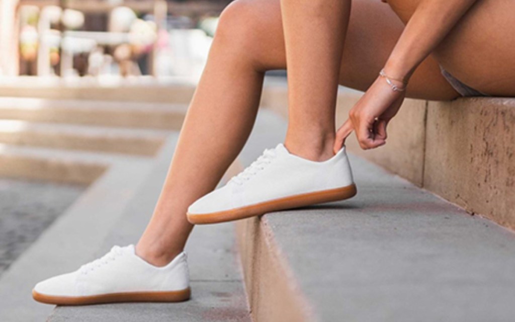 woman putting on white shoes