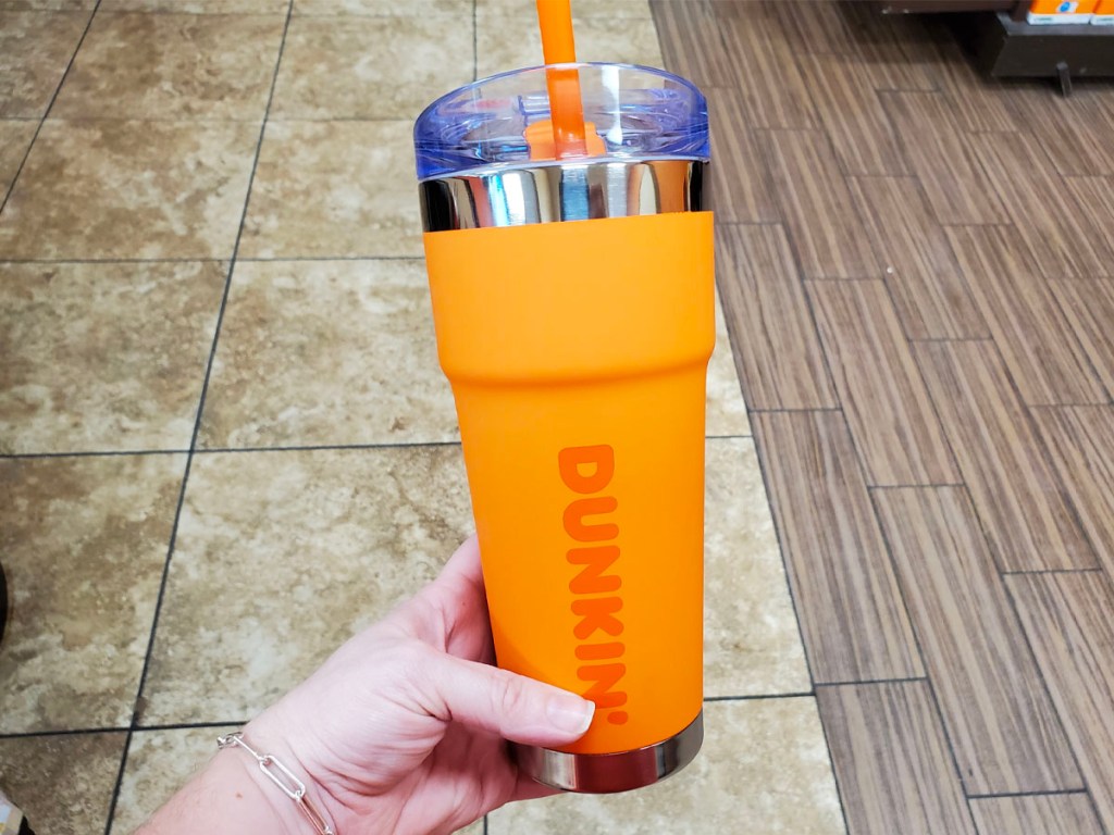 hand holding orange dunkin tumbler