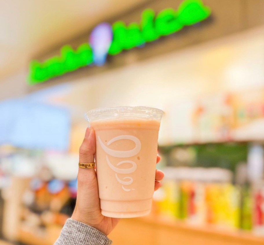 hand holding a jamba juice smoothie in front of sign