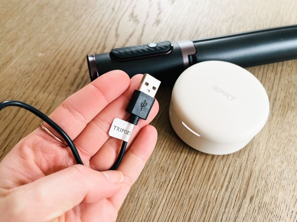 person holdingg cord labeled "tripod" with label maker on desk