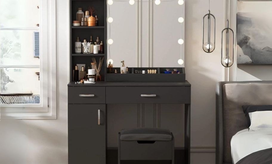 a black vanity desk with lighted mirror