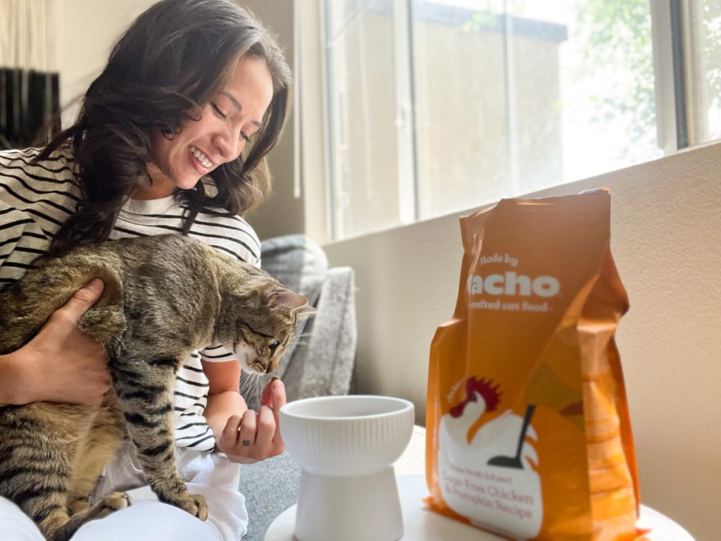 woman holding cat giving dry cat food