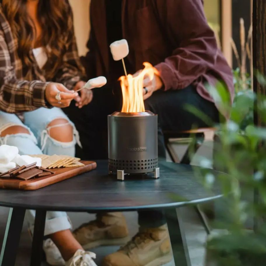 two people roasting marshmallows on a solo stove mesa