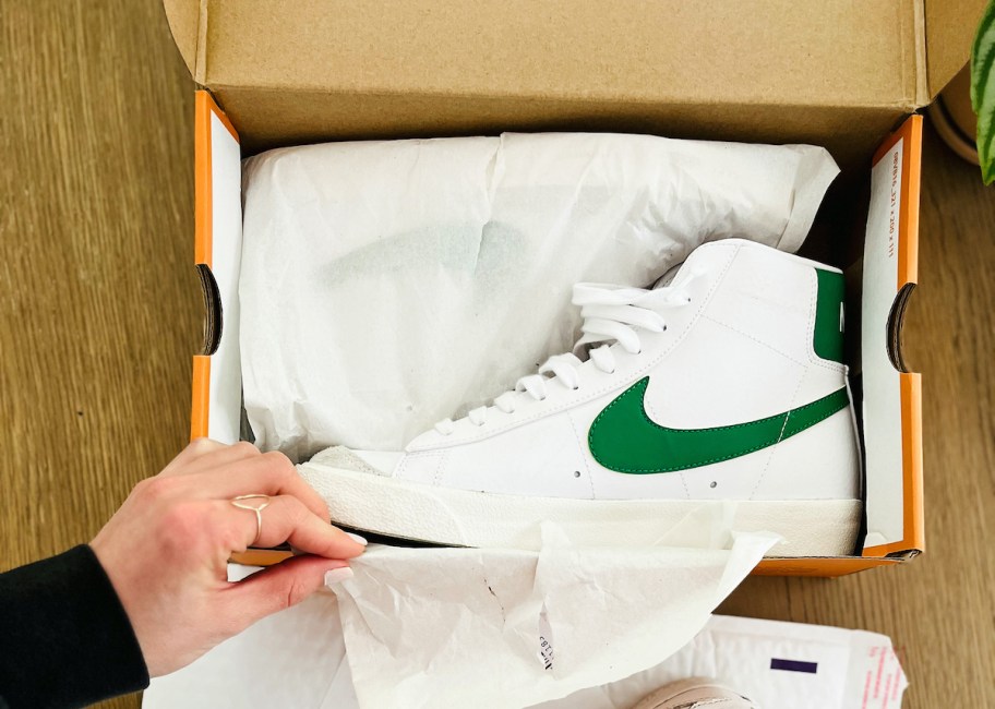 hand holding corner of nike shoebox with white and green nike blazers