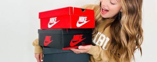 woman holding a stack of black and red nike boxes