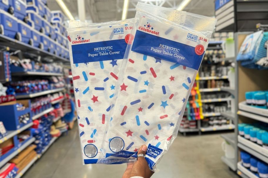 a womans hand holding two patriotic paper table cloths