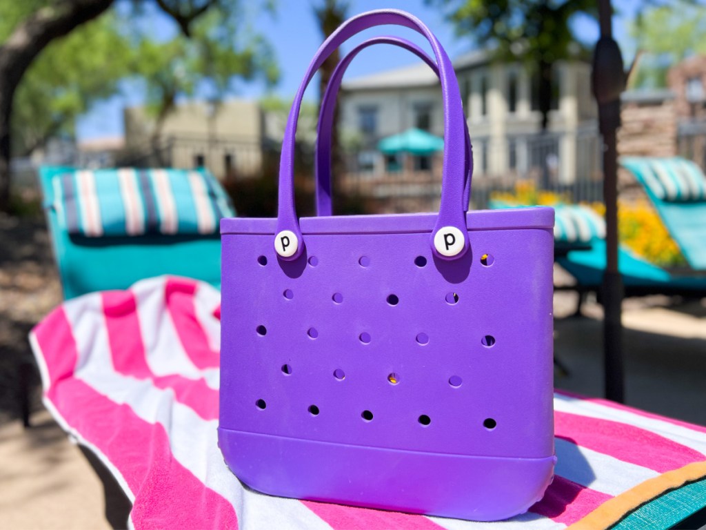 purple beach bag on pink striped towel