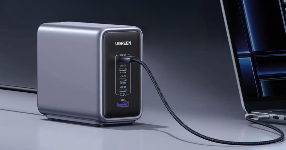 a large black and grey UGREEN desktop charger with multiple ports, one cable going to a laptop