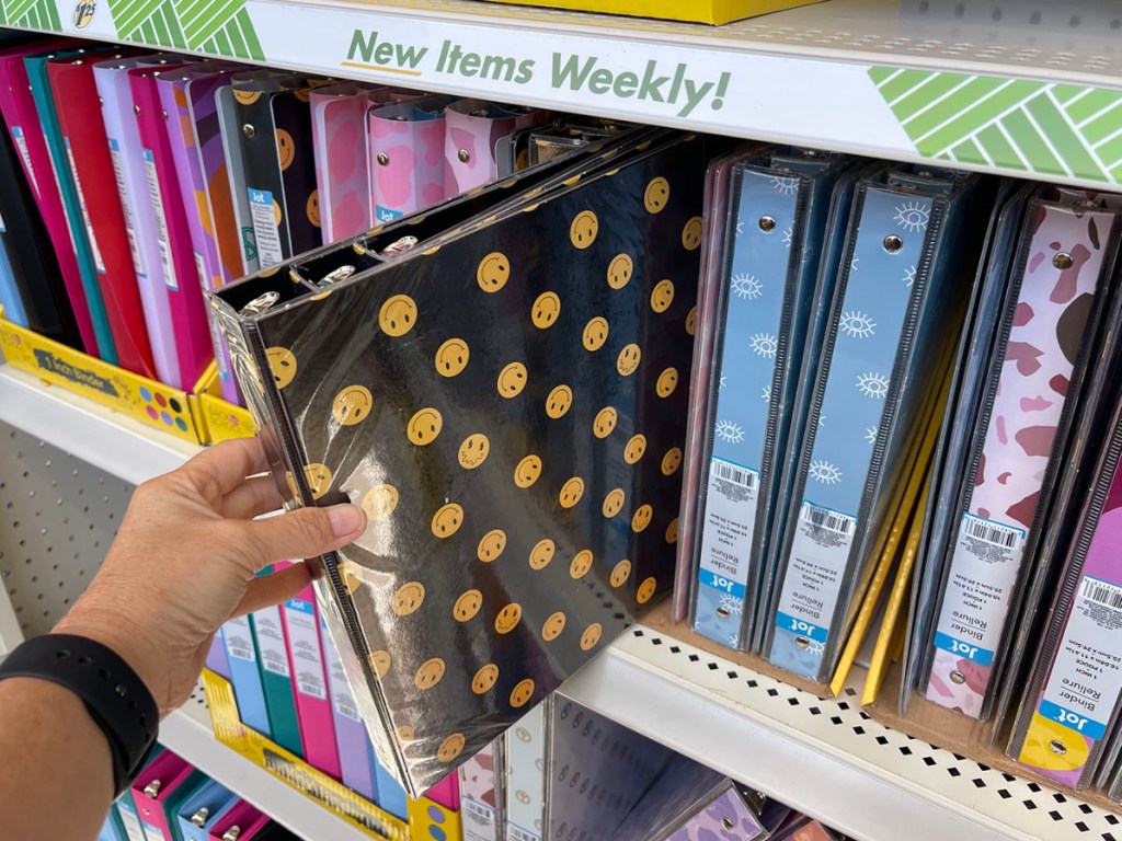 hand taking smiley face 3 ring binder off shelf