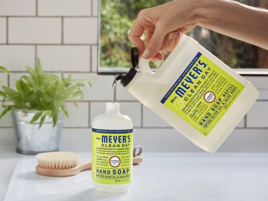 Mrs. Meyer's Hand Soap Refill in Lemon Verbena - 33oz shown being poured into a hand soap bottle