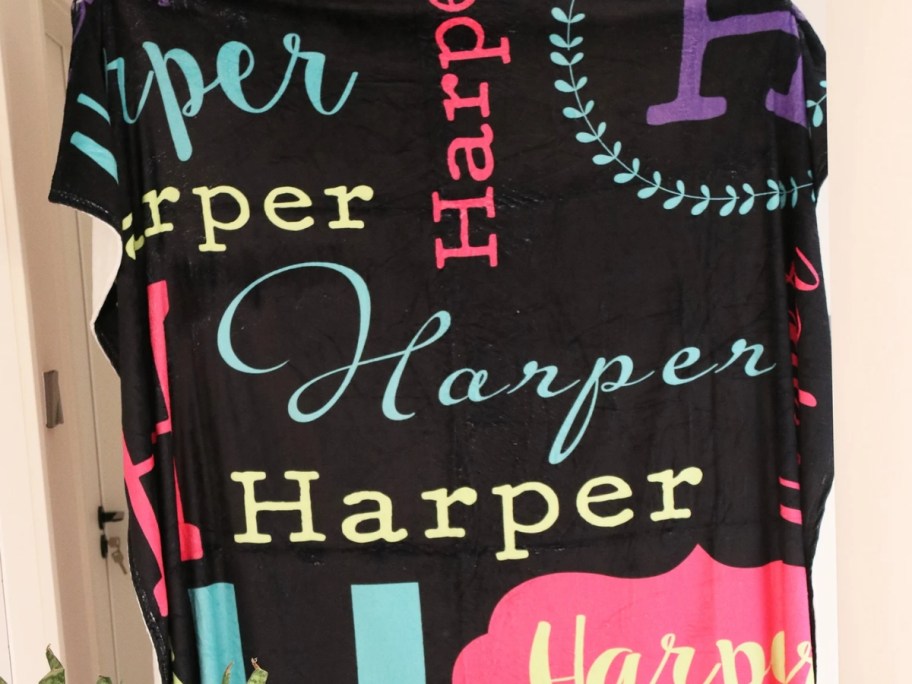 a black throw blanket with the name Harper in various colors and fonts