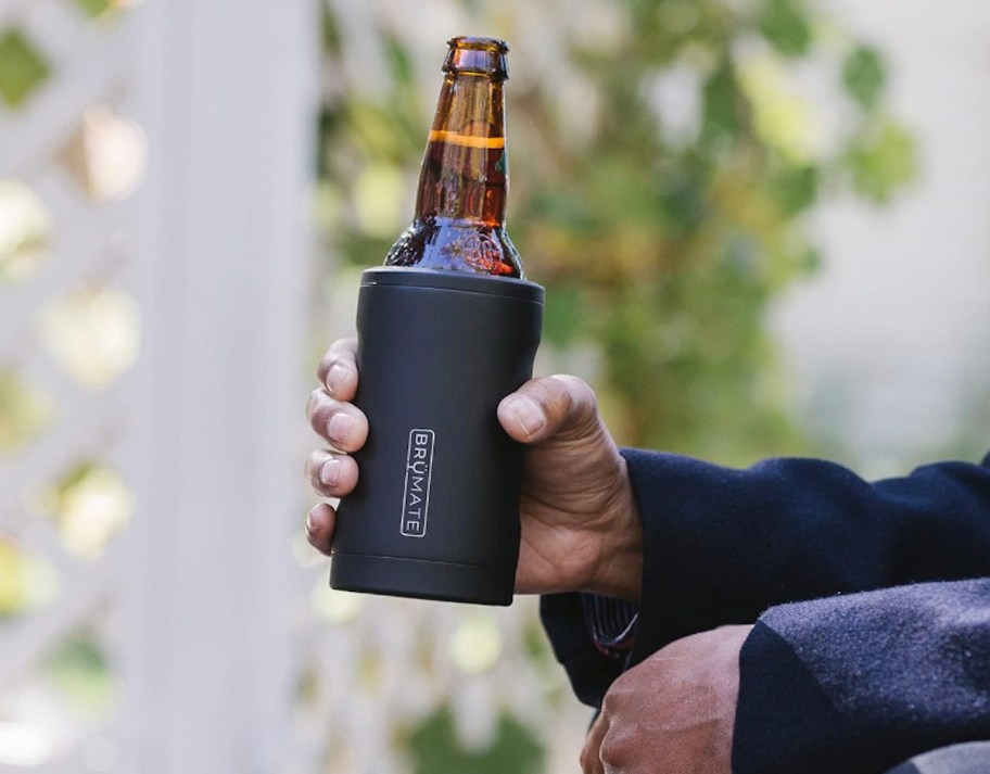 mans hand holding brumate cooler with amber beer bottle inside