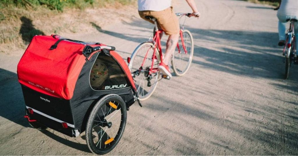 man pulling Burley bike trailor stroller while riding bike