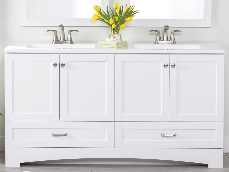 white double vanity with vase of yellow tulips on top