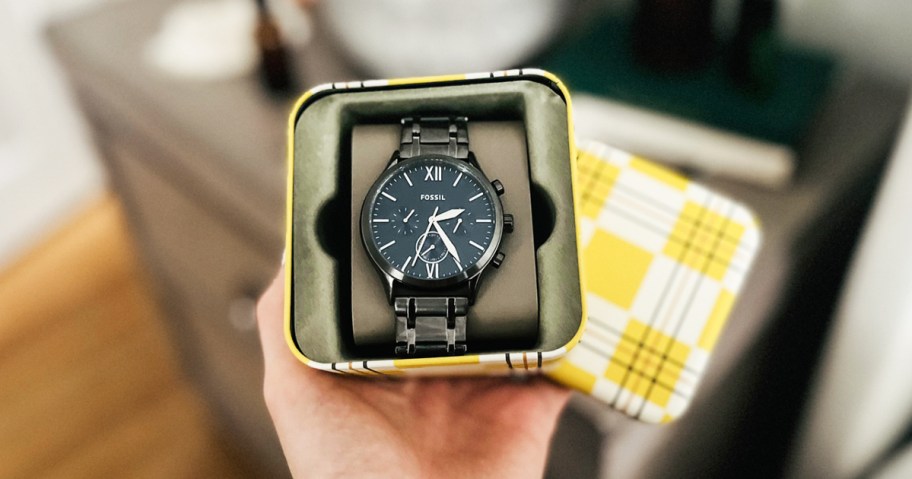 hand holding a gift box with black fossil watch inside