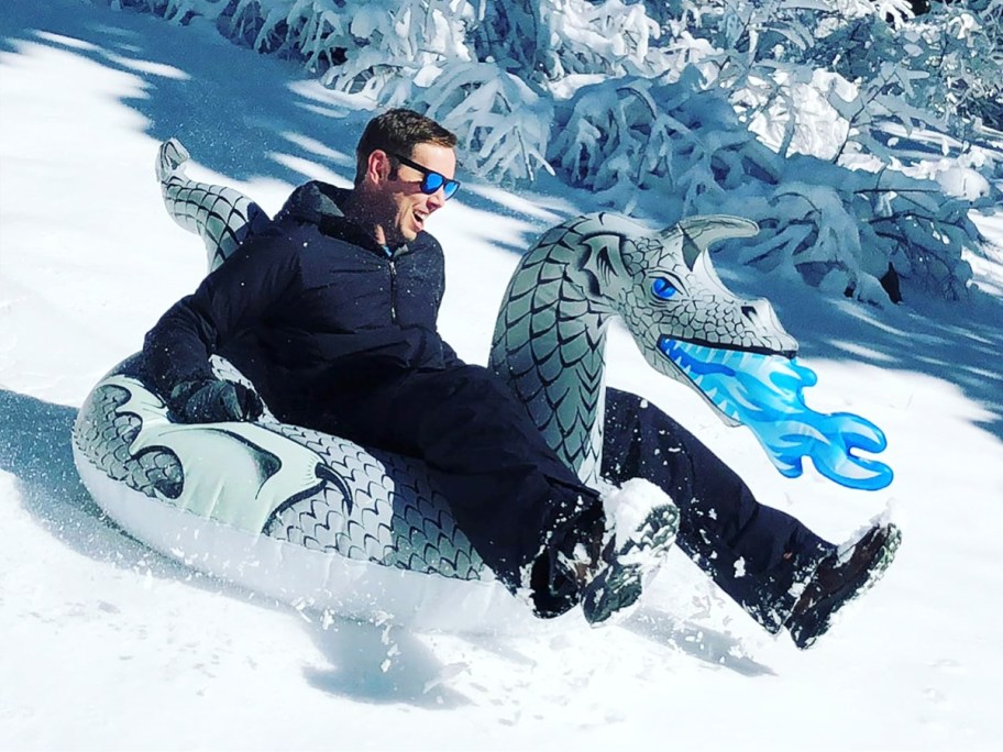 man sledding on a dragon snow tube breathing blue fire