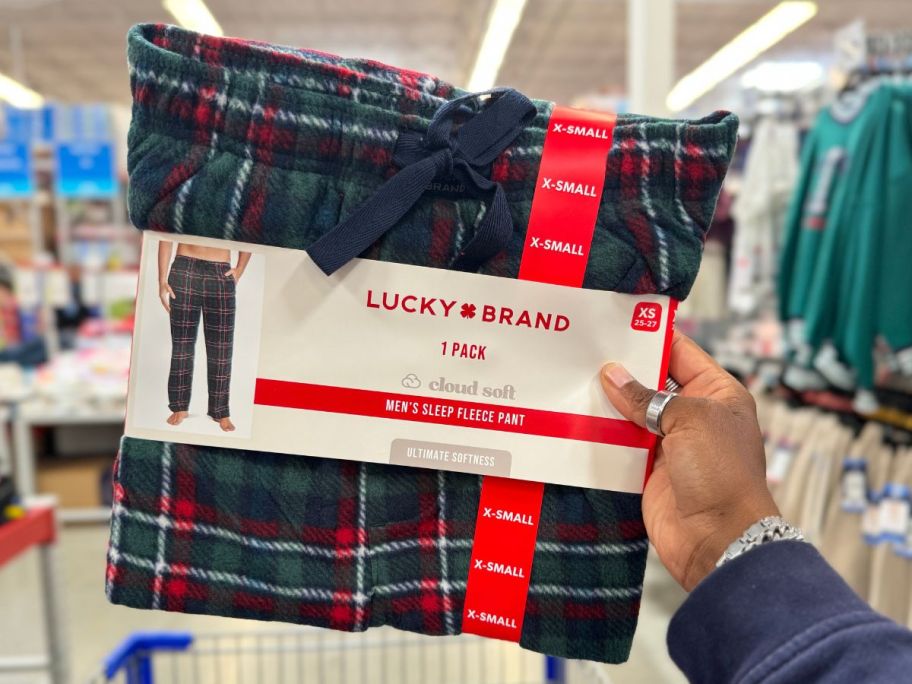 a woman's hand holding a pair of men's plaid fleece sleep pants