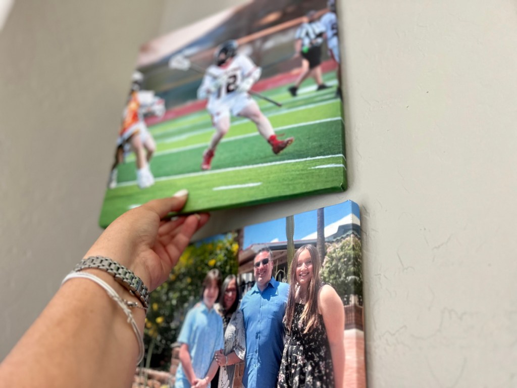 hand placing canvas on wall above another canvas