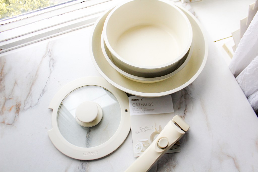 white cookware and pots and pans sitting on white marble countertop