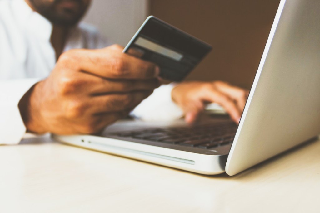 hand holding credit card over laptop