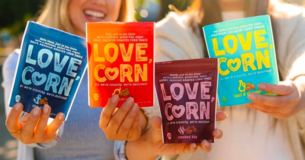 two women holding 4 bags of love corn snack bags