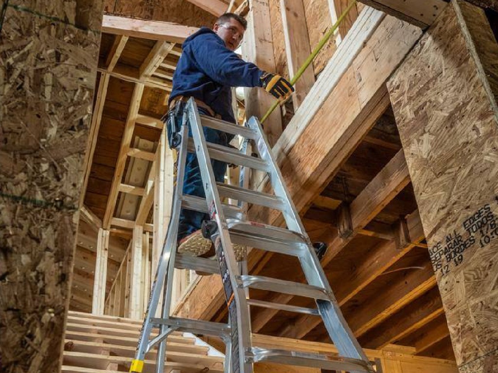 man climbing a ladder inside of house build