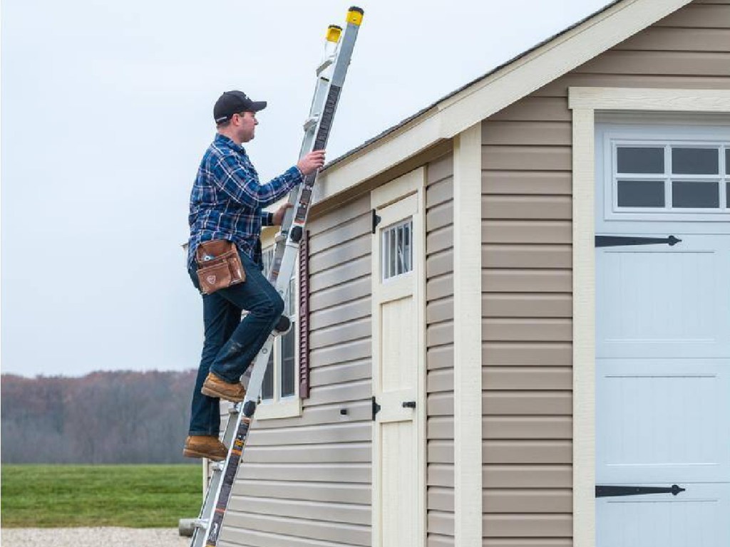 man climbing a ladder outside of a shed