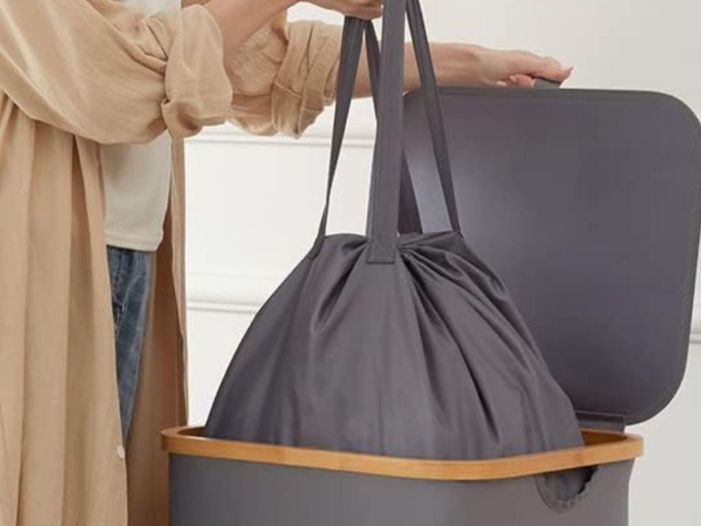 Woman removing the insert of a foldable laundry hamper