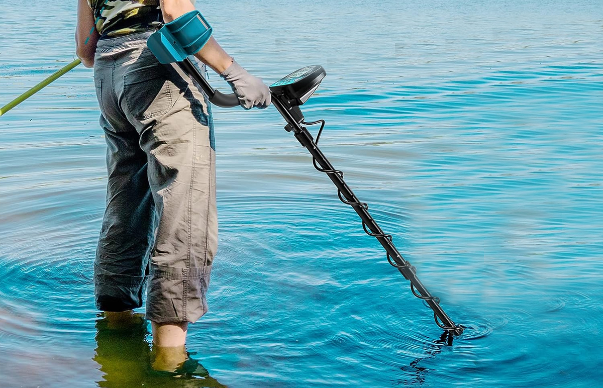 man using metal detector in water