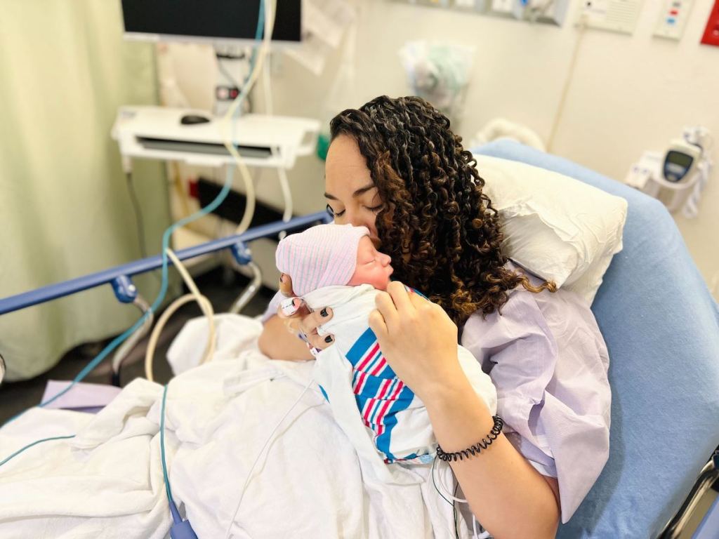 woman sitting in hospital bed holding newborn baby