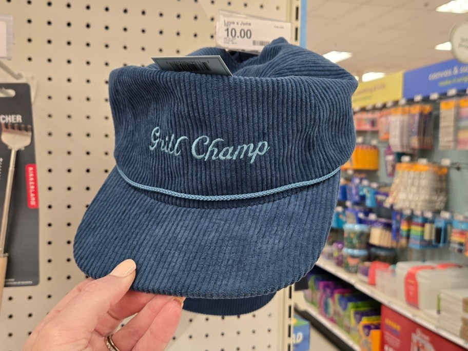 hand holding a blue grill champ hat