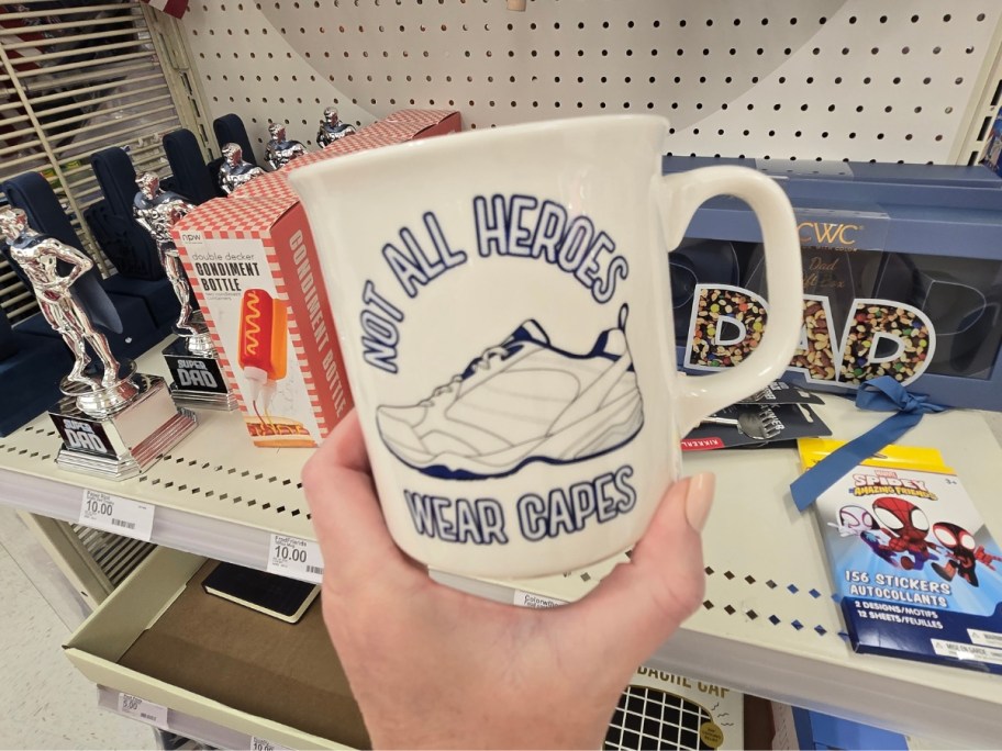 hand holding a coffee mug that says not all heroes wear capes