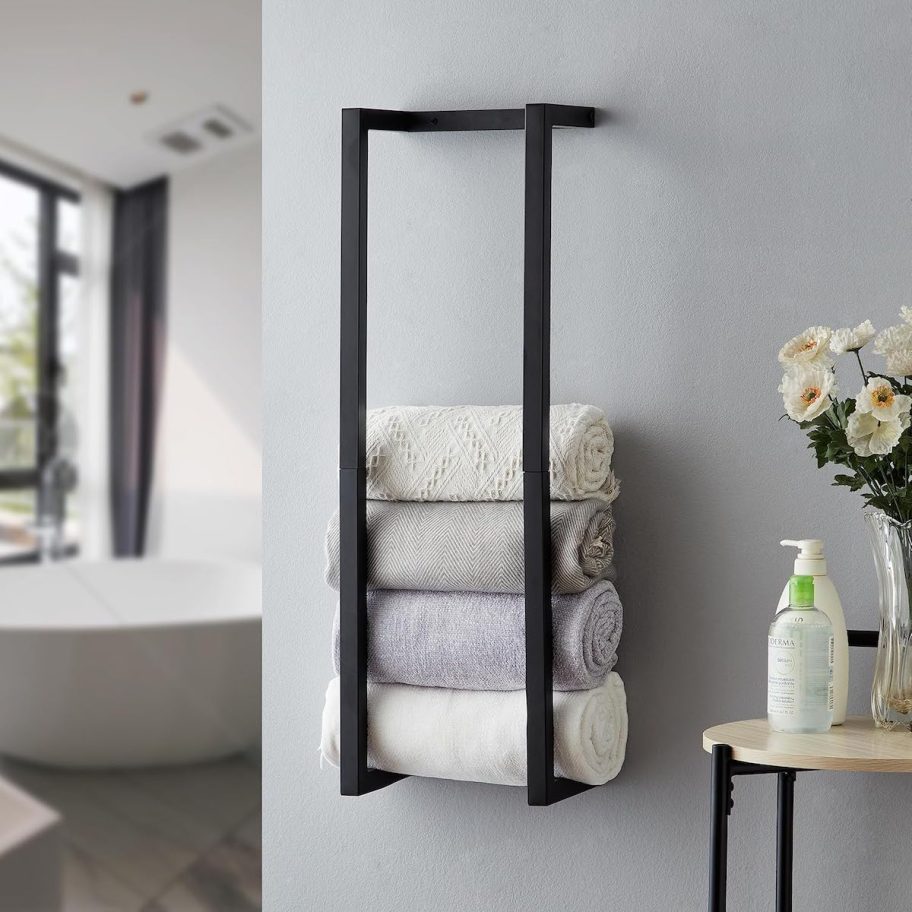 black metal towel rack on wall in bathroom with rolled towels inside