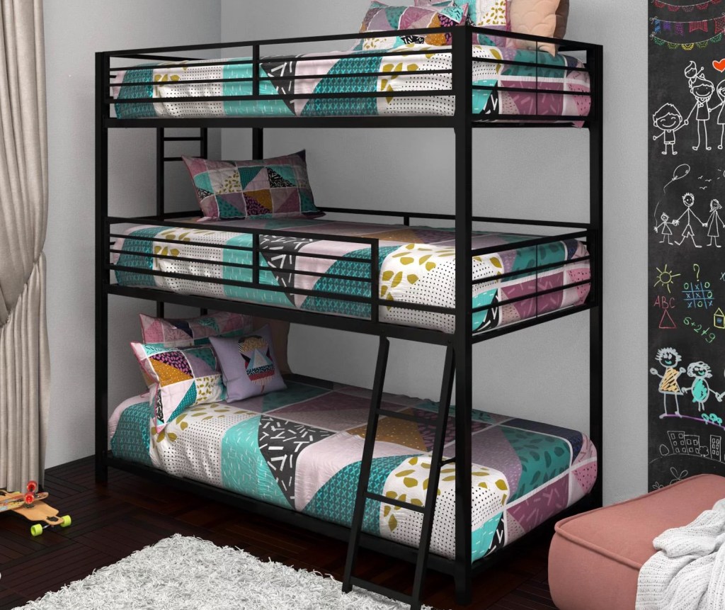 black triple bunk bed against a gray wall with colorful onlineforters and pillows on each mattress