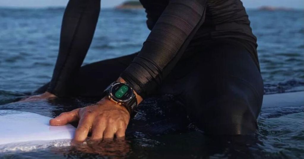 person wearing smartwatch sitting on surfboard