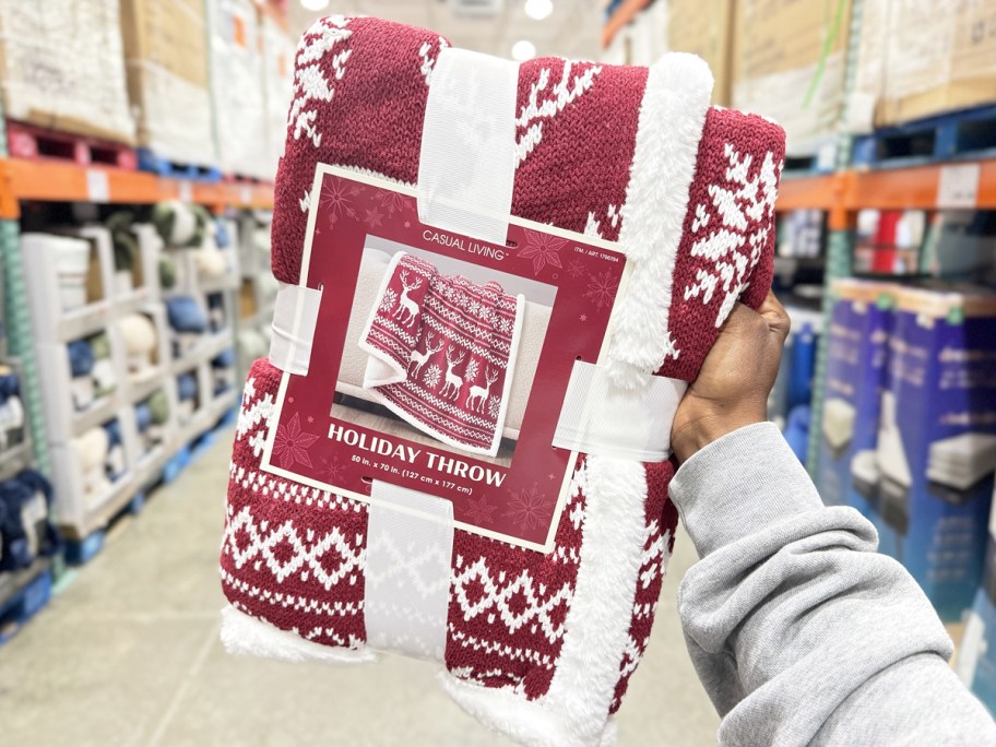 hand holding up a red and white holiday throw blanket