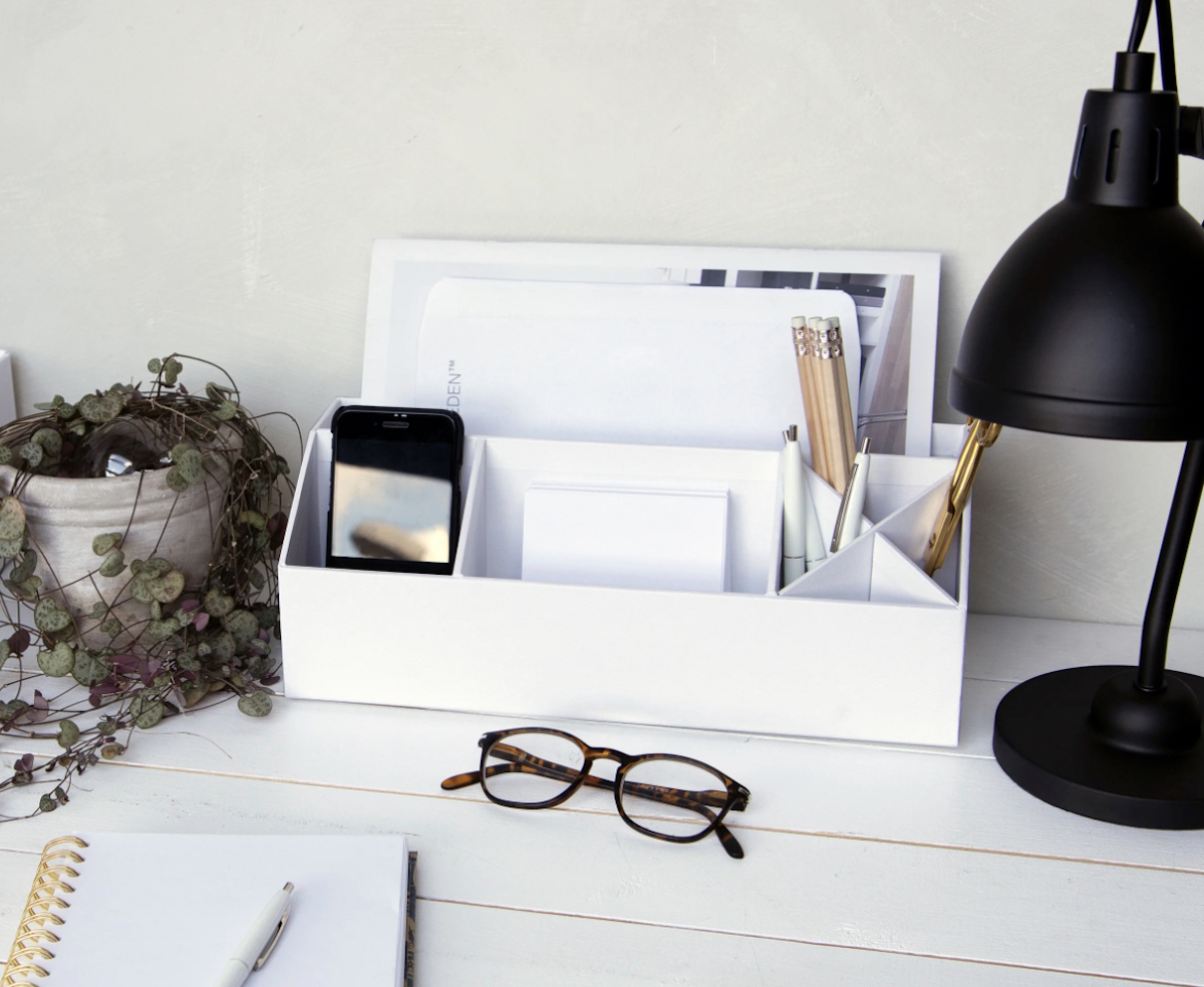 white desk organizer with phone paper and pens 