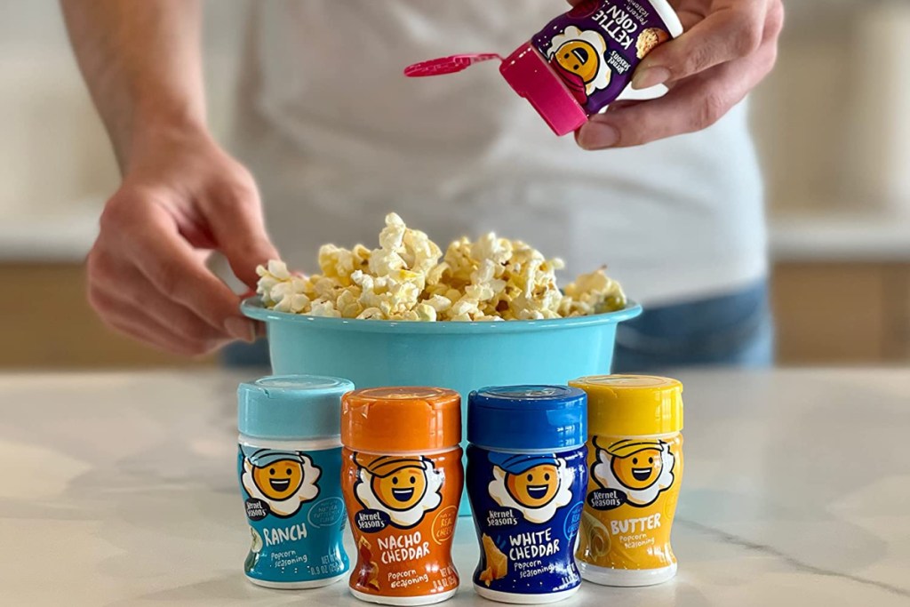 Man sprinkling Kernel Season Popcorn Seasoning onto a bowl of fresh popcorn