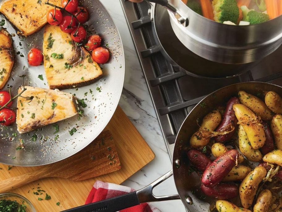 A person cooking a delightful meal on their cooktop with KitchenAid Stainless Steel 10 Piece Pots and Pans