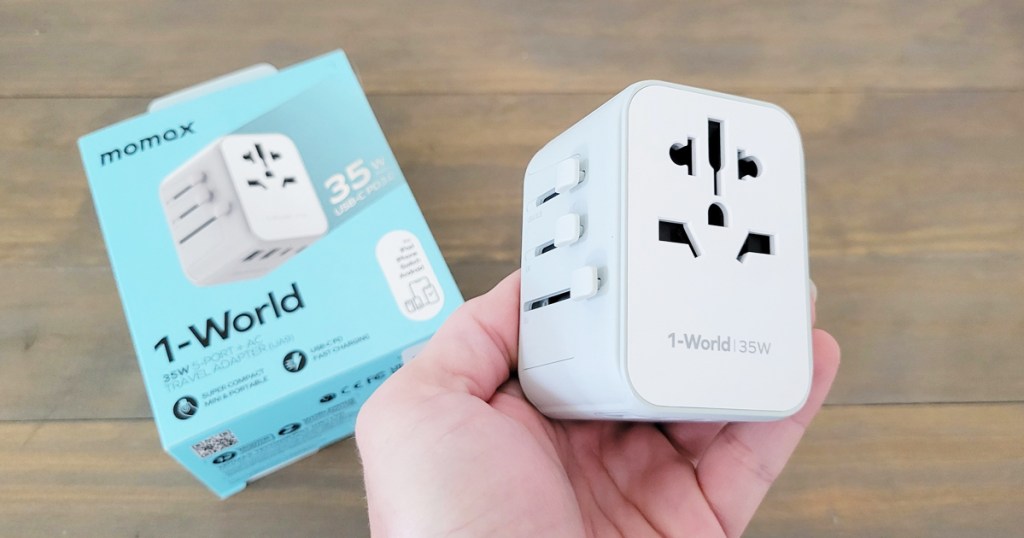 hand holding a white travel adapter plug