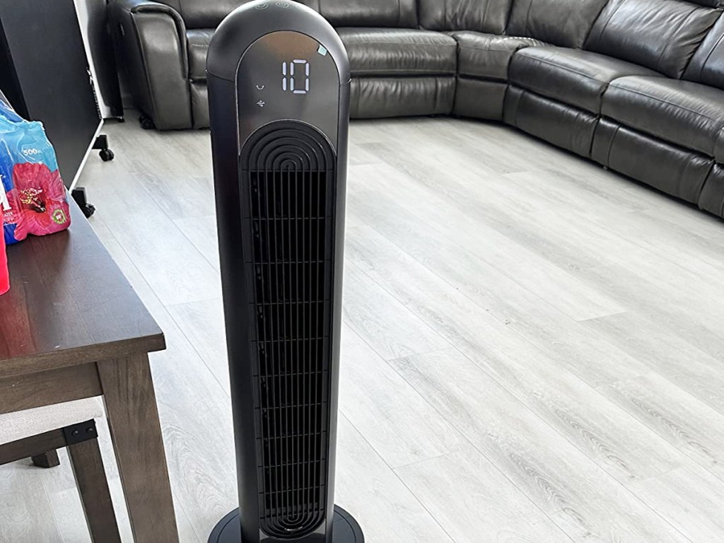 black tower fan in a living room with a black leather couch in background